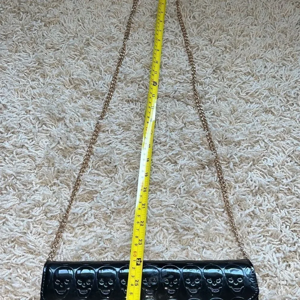 Awesome patent leather skull embossed clutch bag with gold chain shoulder strap.